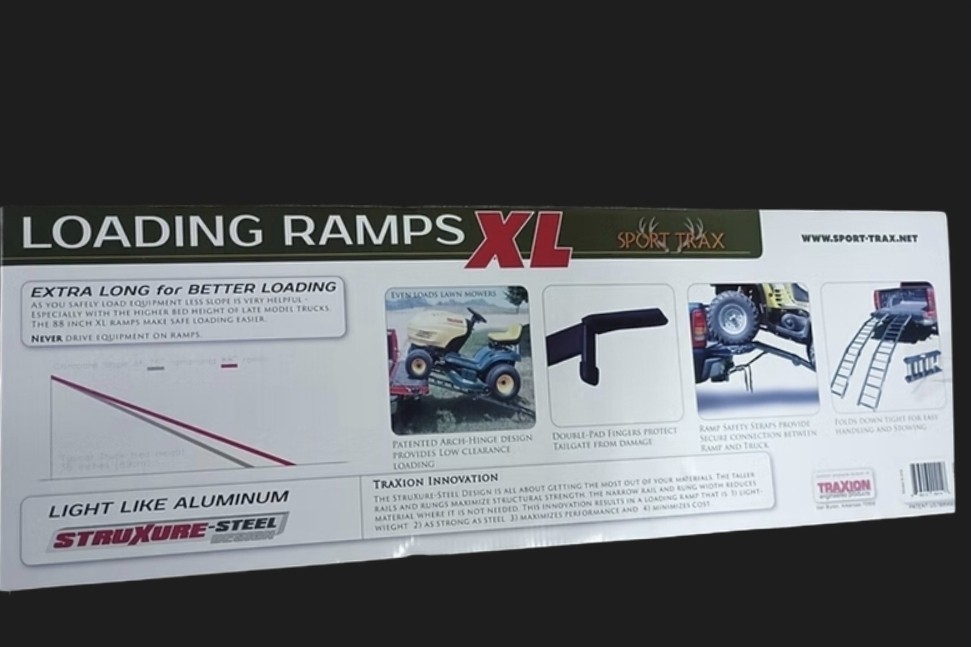 A pair of Sport Trax heavy-duty XL loading ramps leaning against the open tailgate of a pickup truck.